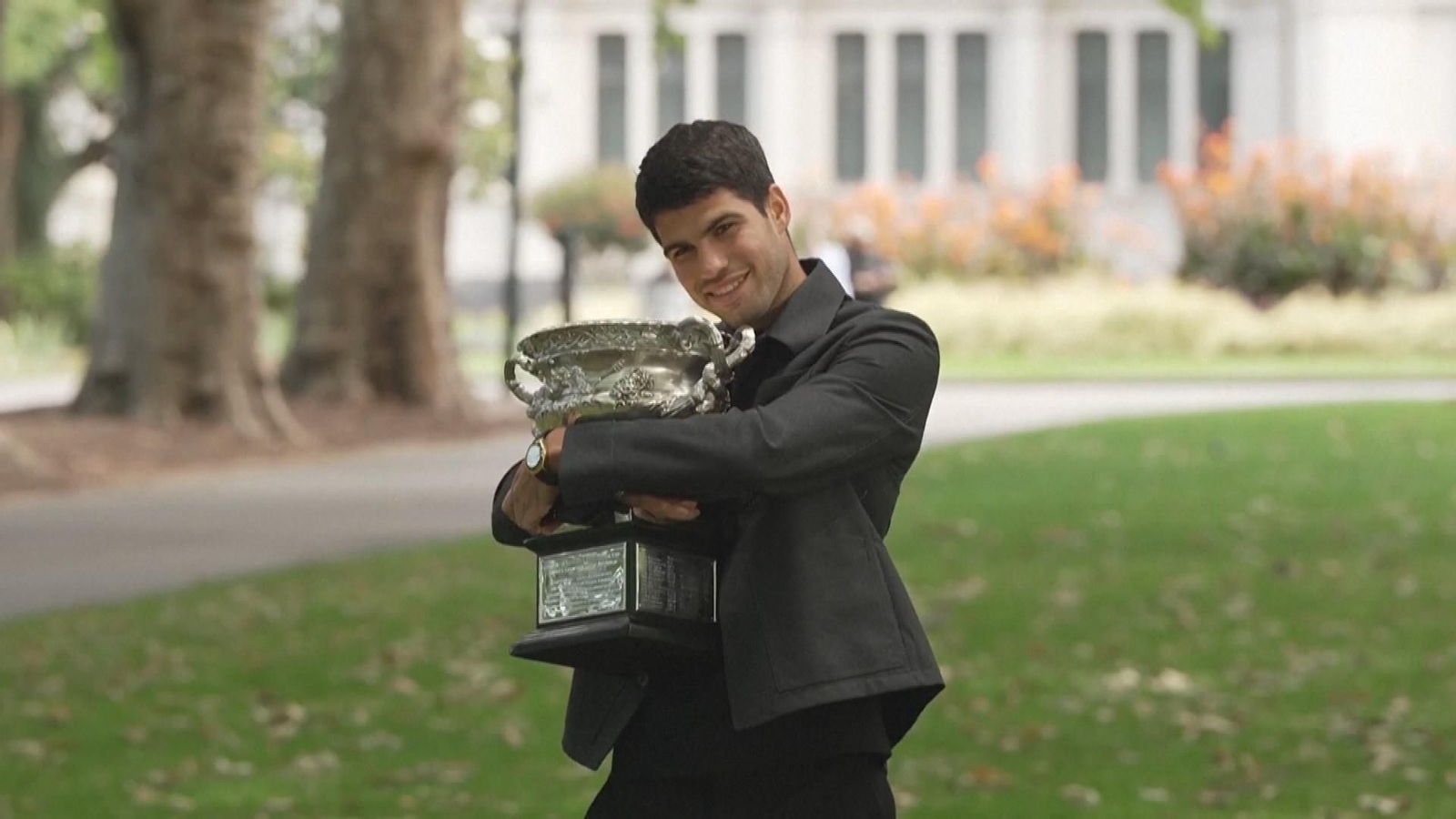 Alcaraz celebra su victoria en el Open de Australia posando con el trofeo